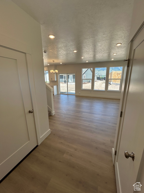 Corridor with light wood-type flooring, recessed lighting, baseboards, and a chandelier
