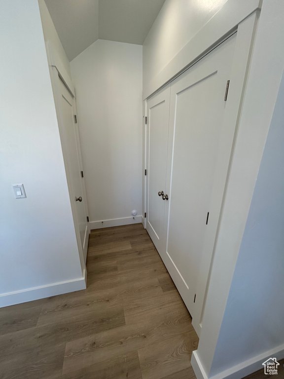 Hallway with wood finished floors, baseboards, and vaulted ceiling