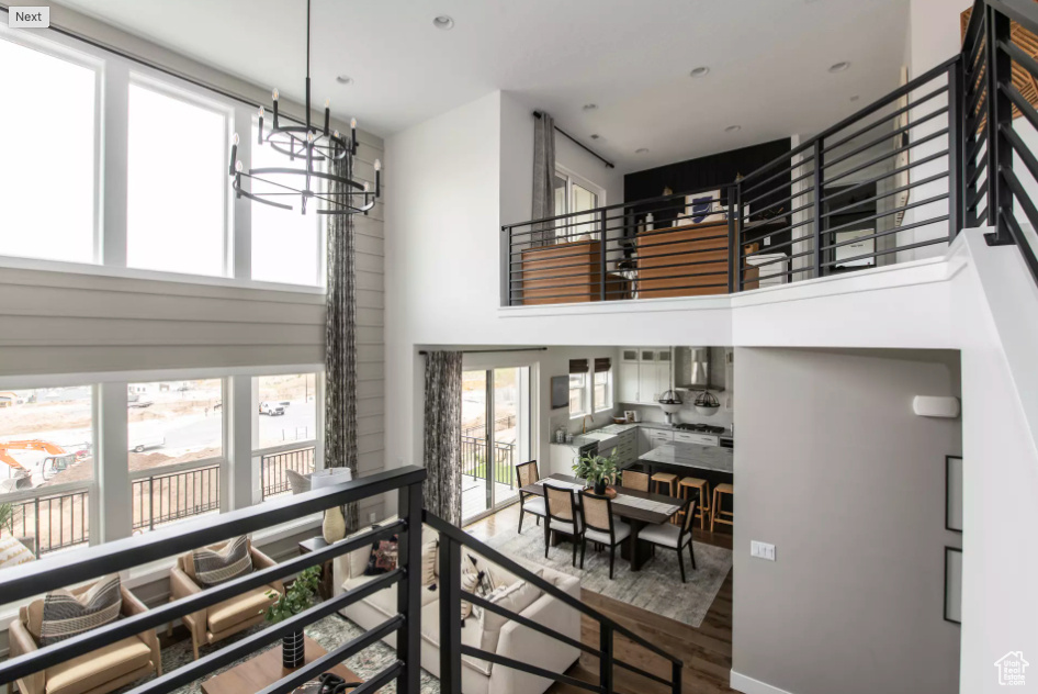Stairway with a towering ceiling, wood finished floors, and a chandelier