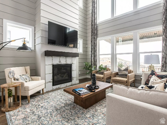 Living area featuring a fireplace, a high ceiling, wood finished floors, and wood walls