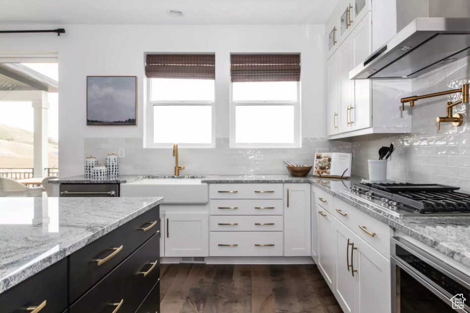 Kitchen featuring wall chimney exhaust hood, stainless steel gas cooktop, plenty of natural light, and a sink