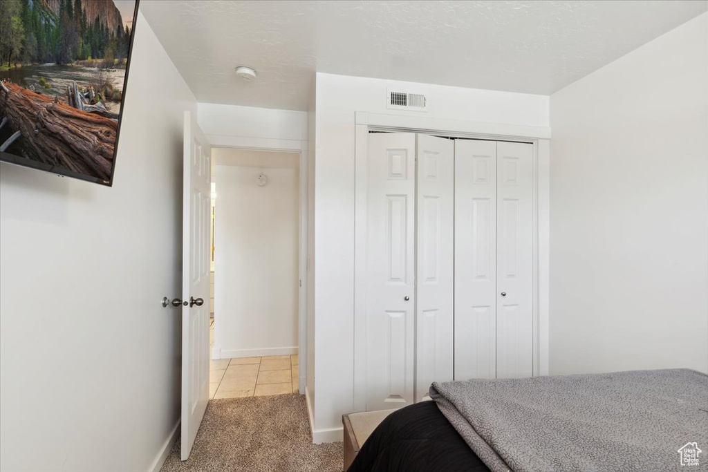 Bedroom with carpet, a closet, baseboards, and tile patterned flooring
