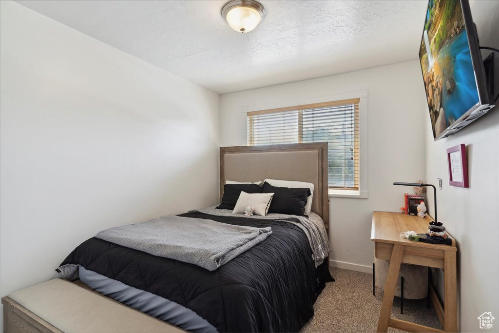 Bedroom with carpet, baseboards, and a textured ceiling