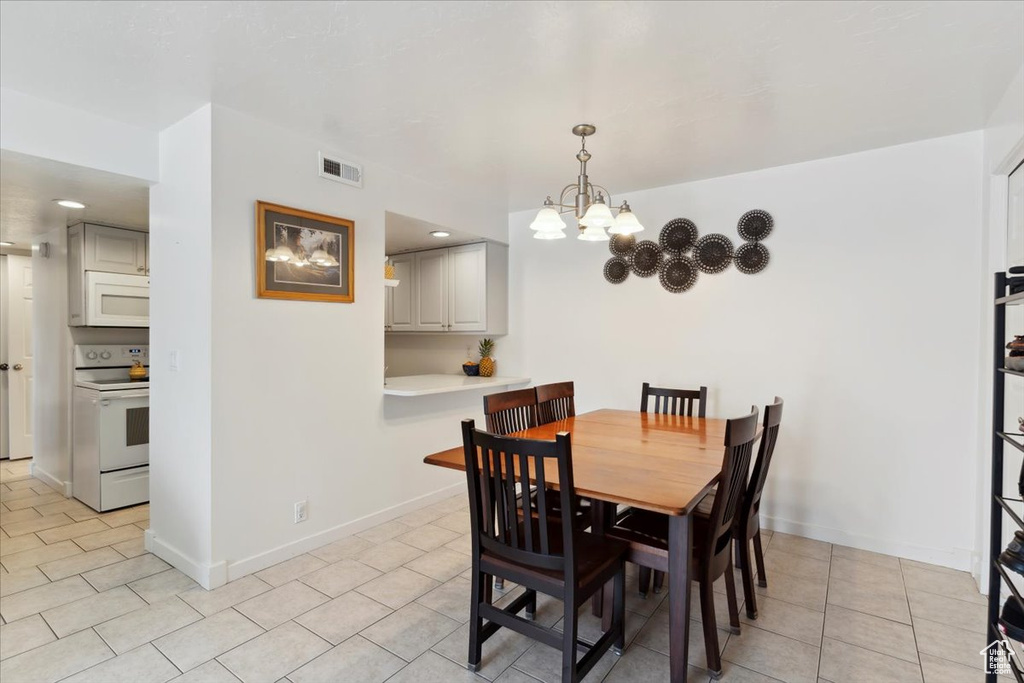 Dining area featuring light tile patterned floors, a chandelier, and baseboards