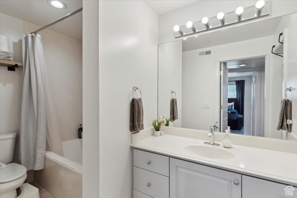 Bathroom with toilet, vanity, and shower / bath combo with shower curtain