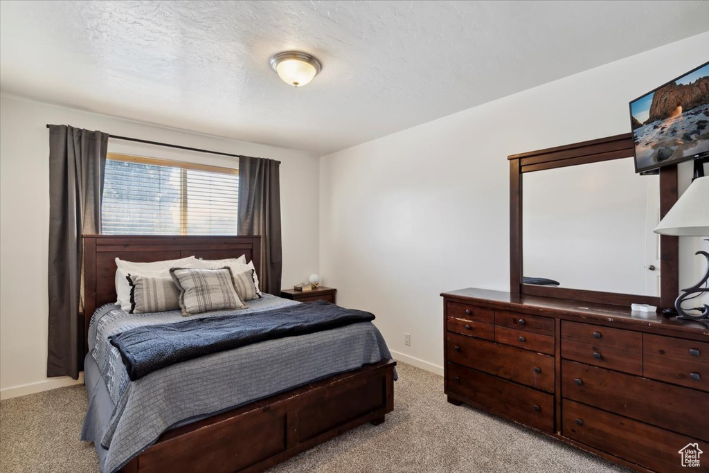 Bedroom featuring light colored carpet, baseboards, and a textured ceiling