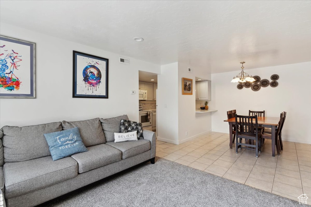 Living room with light tile patterned floors, a chandelier, light colored carpet, and recessed lighting