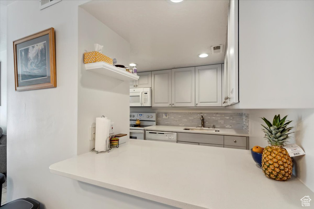 Kitchen featuring white appliances, a sink, light countertops, tasteful backsplash, and recessed lighting