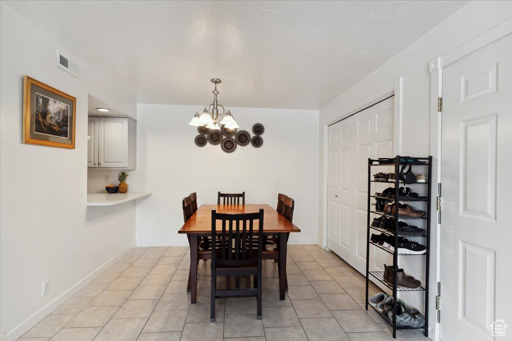 Dining area with a chandelier, light tile patterned flooring, and baseboards