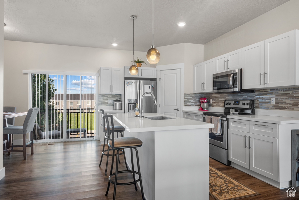 Kitchen with appliances with stainless steel finishes, a sink, decorative backsplash, a breakfast bar area, and recessed lighting