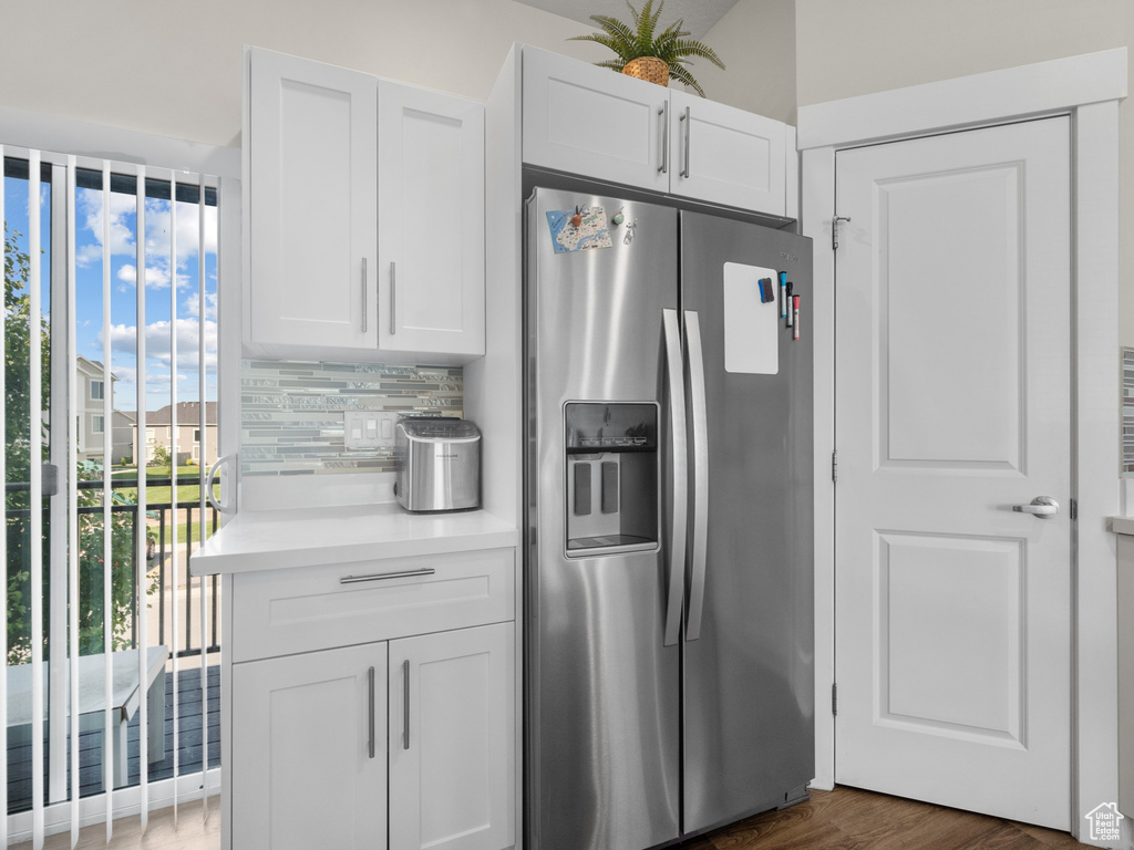 Kitchen featuring stainless steel fridge with ice dispenser, backsplash, light countertops, white cabinetry, and wood finished floors