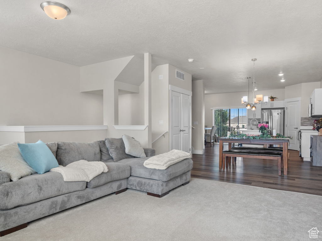 Living room with dark carpet, a chandelier, and dark wood-style flooring