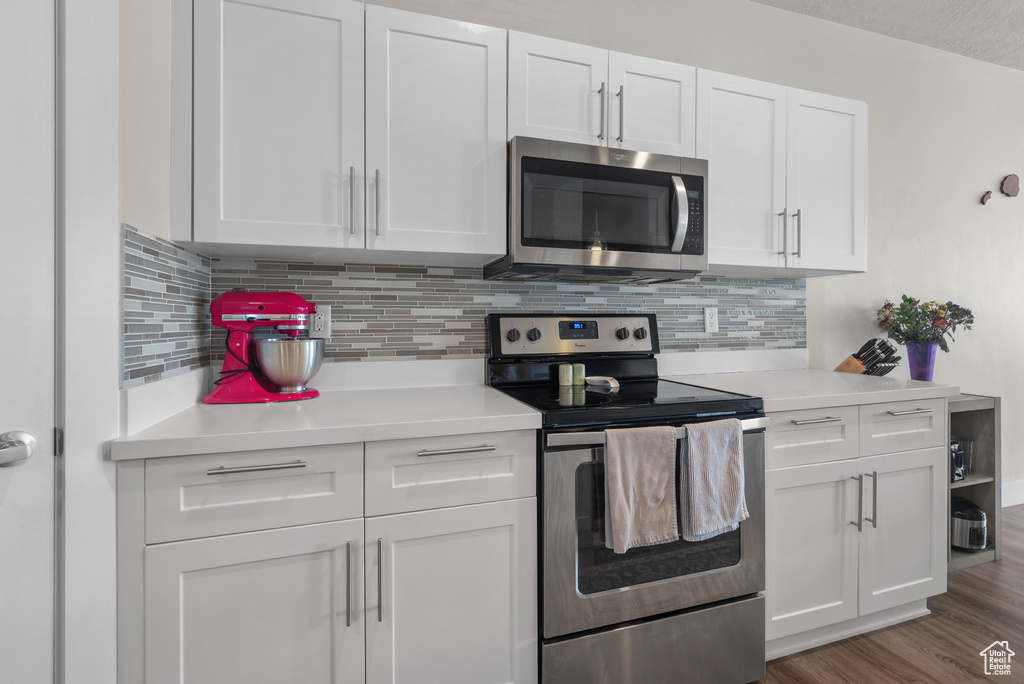 Kitchen with appliances with stainless steel finishes, white cabinets, light countertops, and decorative backsplash