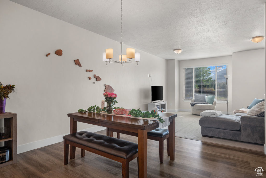 Dining room featuring a textured ceiling, a chandelier, wood finished floors, and baseboards