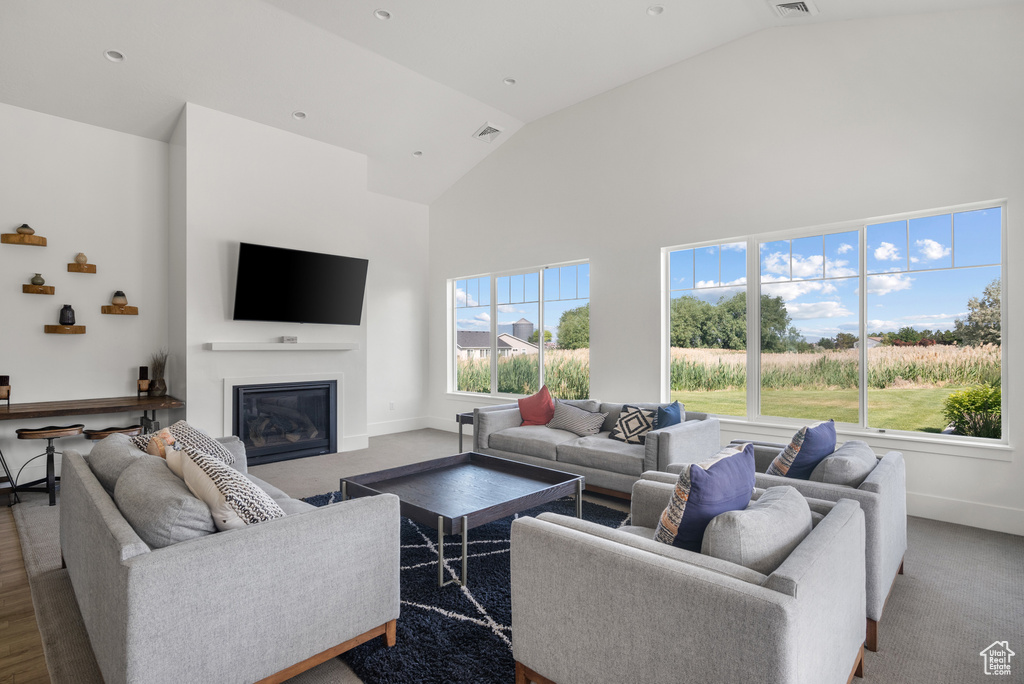 Living room featuring high vaulted ceiling, baseboards, and a glass covered fireplace