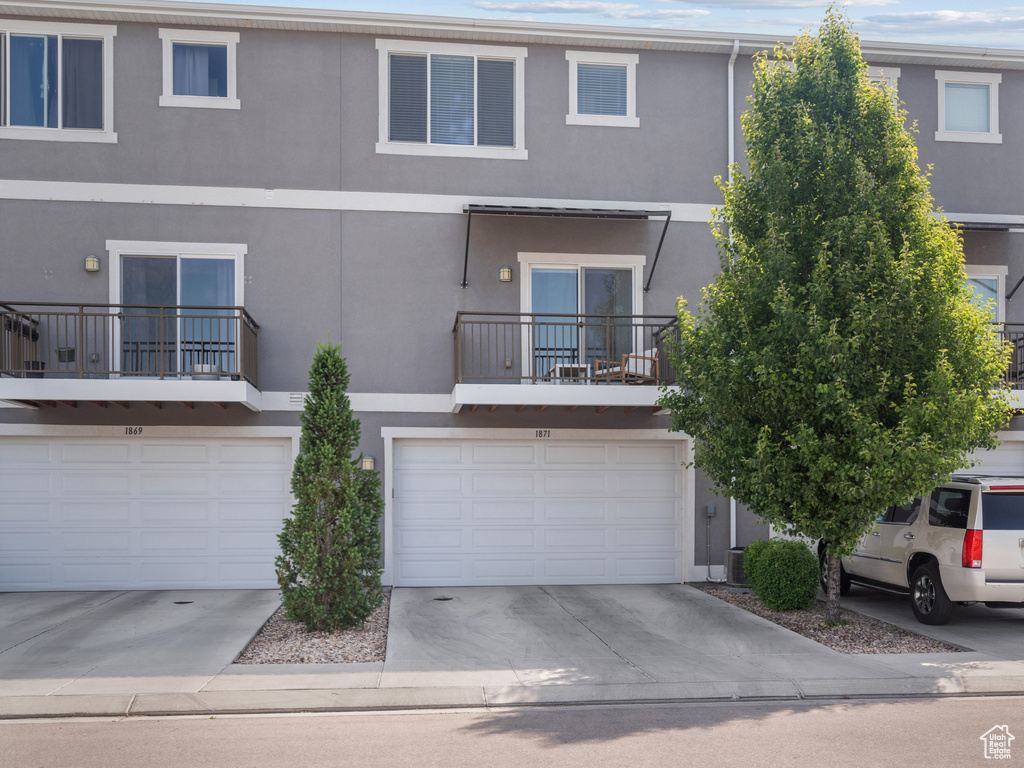 Multi unit property featuring stucco siding, a garage, and concrete driveway