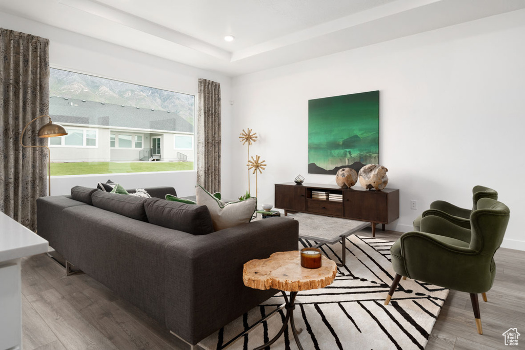 Living room featuring wood finished floors, recessed lighting, a tray ceiling, and baseboards