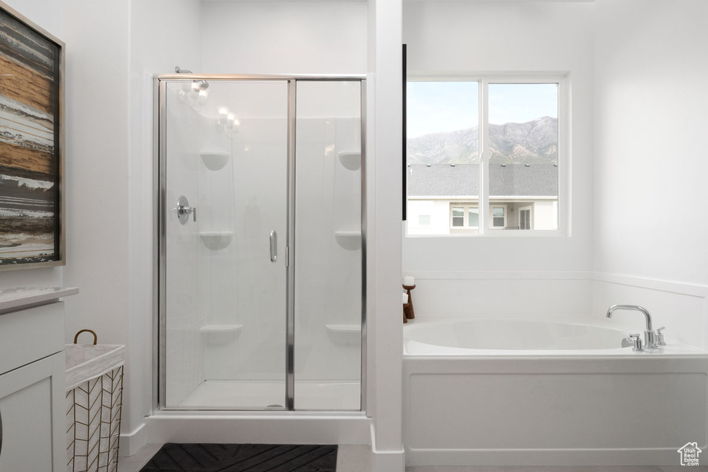 Bathroom featuring a stall shower, a bath, and a mountain view