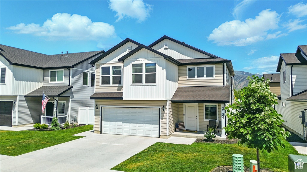 Townhome / multi-family property featuring board and batten siding, a garage, driveway, and a front yard