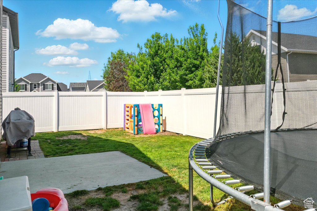 View of yard with a trampoline and a patio