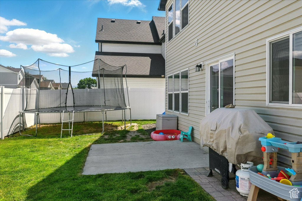 View of yard with a trampoline and a patio area