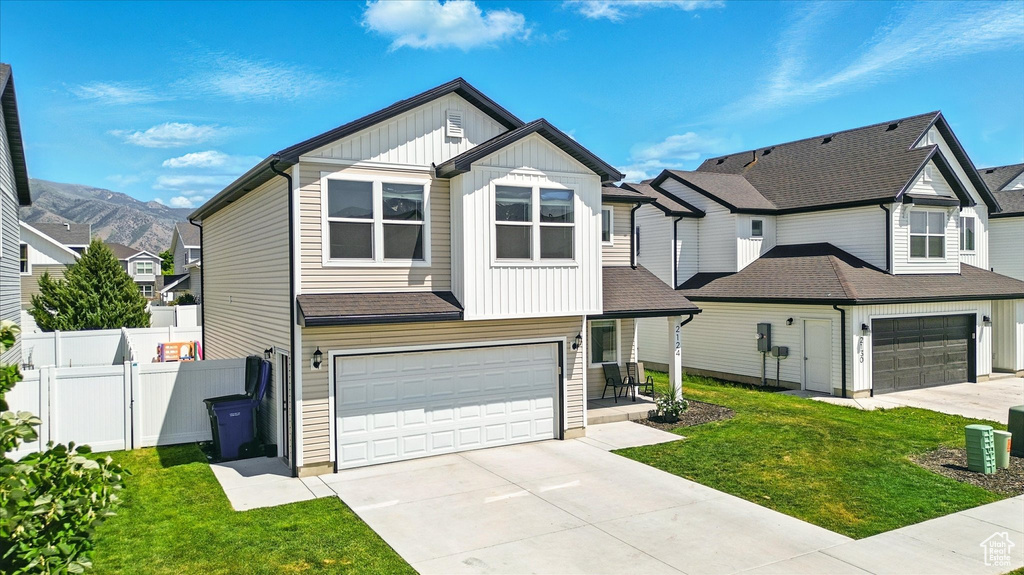 View of front of property featuring board and batten siding, a garage, concrete driveway, and a residential view