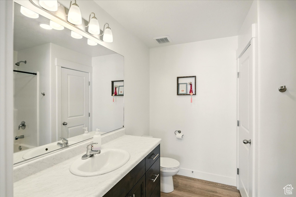 Full bath with vanity, wood finished floors, toilet, baseboards, and tub / shower combination