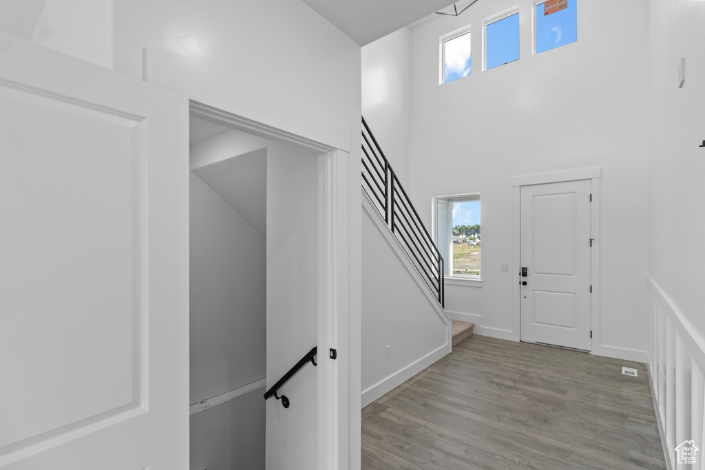 Entrance foyer with wood finished floors, plenty of natural light, baseboards, stairway, and a towering ceiling
