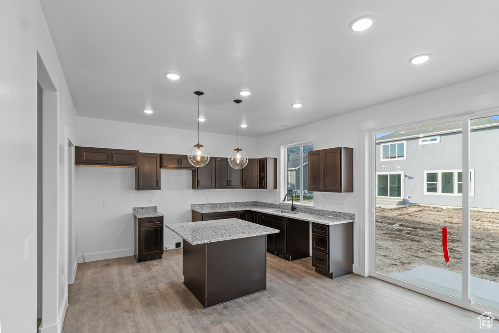 Kitchen with dark brown cabinets, a kitchen island, a sink, recessed lighting, and light wood finished floors