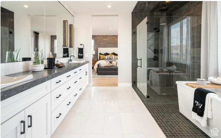 Ensuite bathroom featuring double vanity, a shower stall, and recessed lighting