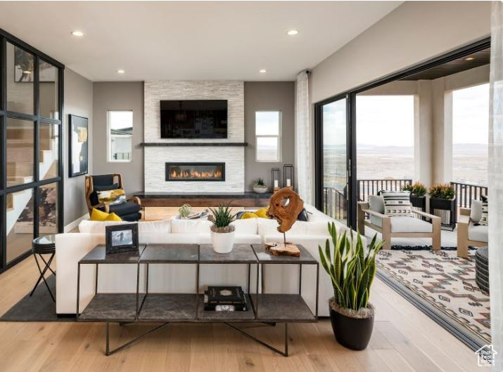 Living room with plenty of natural light, wood finished floors, a large fireplace, and recessed lighting