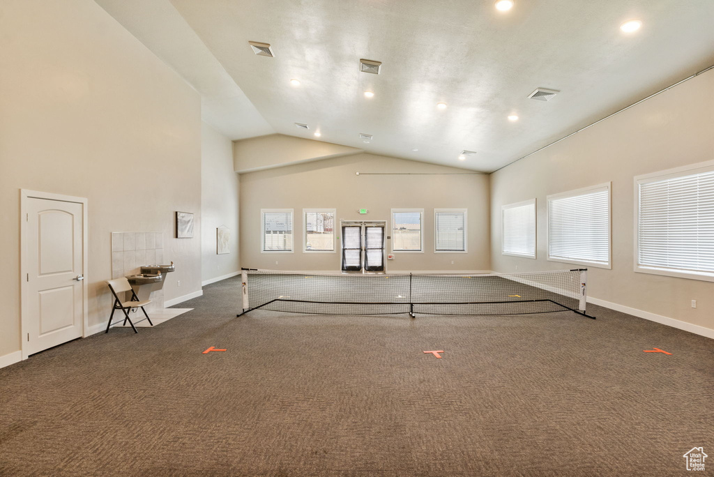 Unfurnished living room with dark colored carpet, high vaulted ceiling, recessed lighting, and baseboards