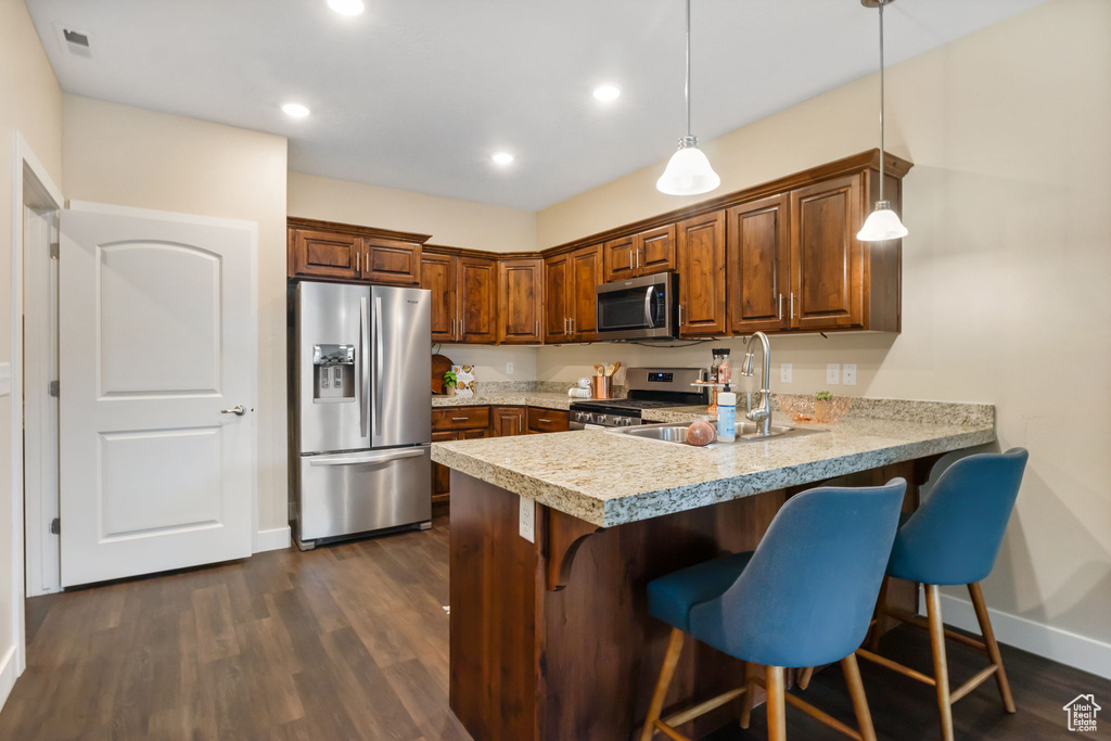 Kitchen featuring stainless steel appliances, light countertops, a kitchen bar, a peninsula, and baseboards
