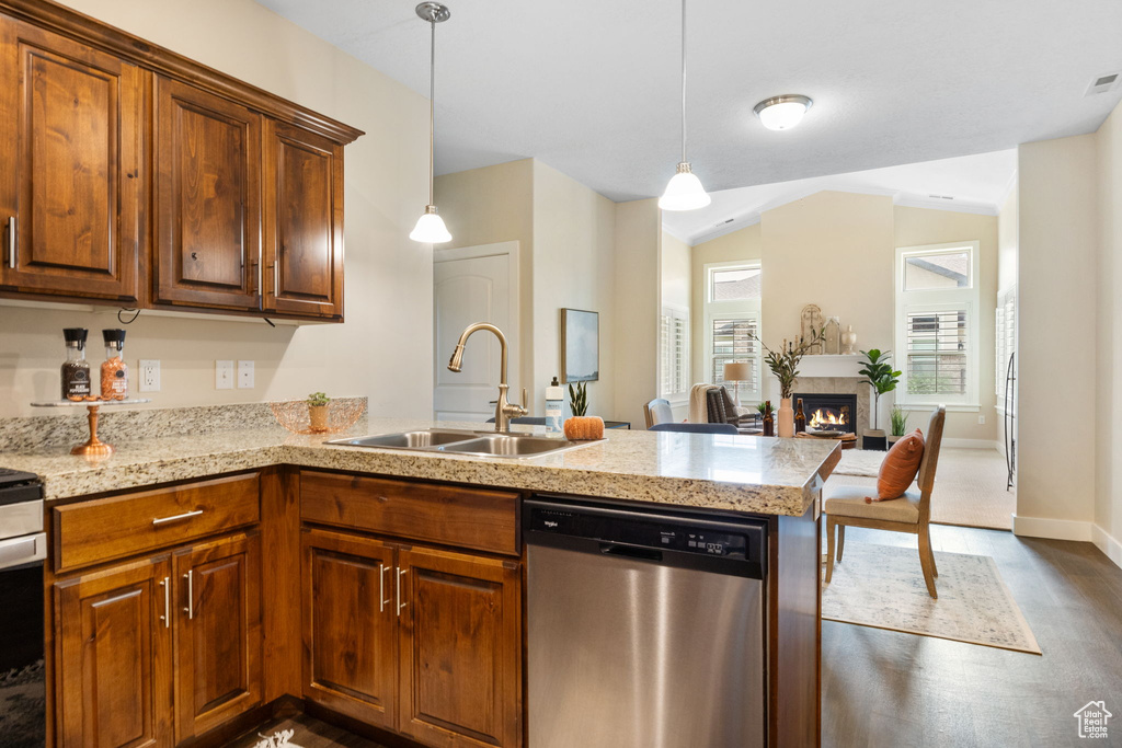 Kitchen featuring dishwasher, a sink, a peninsula, dark wood-style floors, and a warm lit fireplace