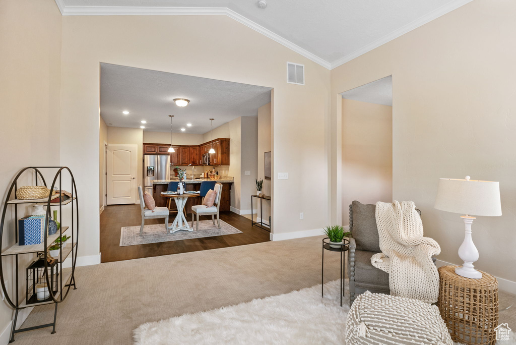 Living room featuring dark colored carpet, baseboards, vaulted ceiling, and ornamental molding