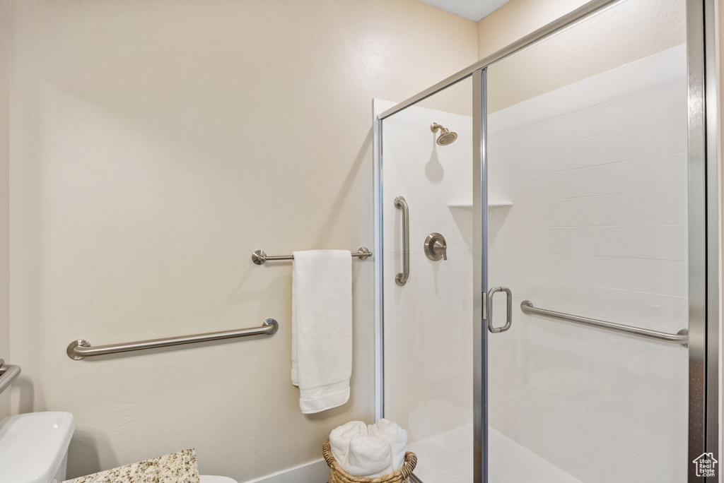 Bathroom featuring toilet, a stall shower, and baseboards