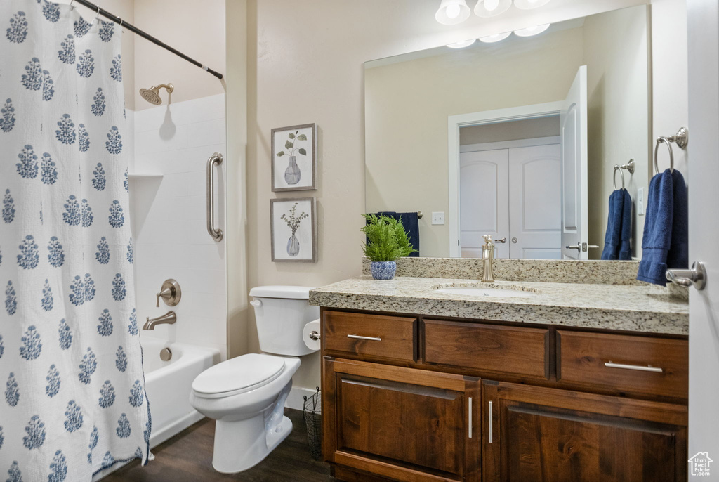 Bathroom with vanity, toilet, wood finished floors, and shower / bath combo