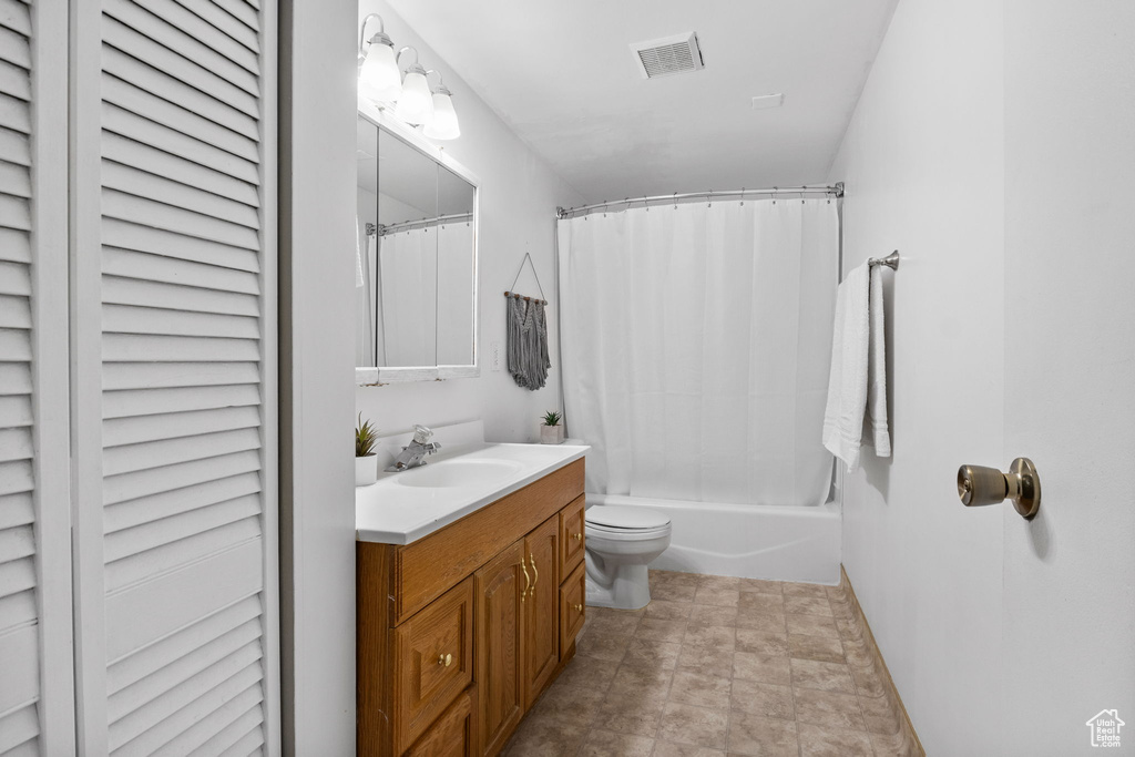 Bathroom featuring vanity, toilet, shower / bath combination with curtain, baseboards, and a closet