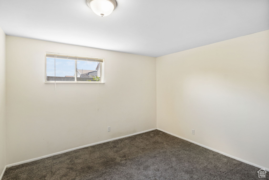 Empty room featuring dark colored carpet and baseboards