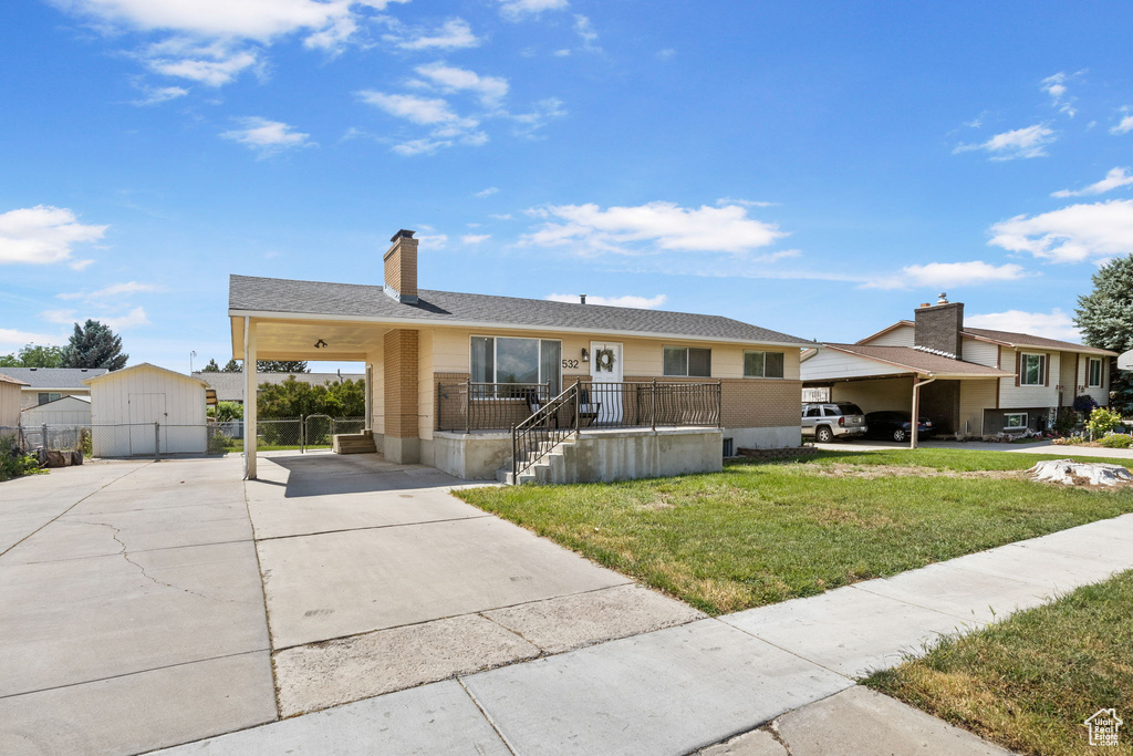 View of front of house featuring driveway, a chimney, and an outdoor structure