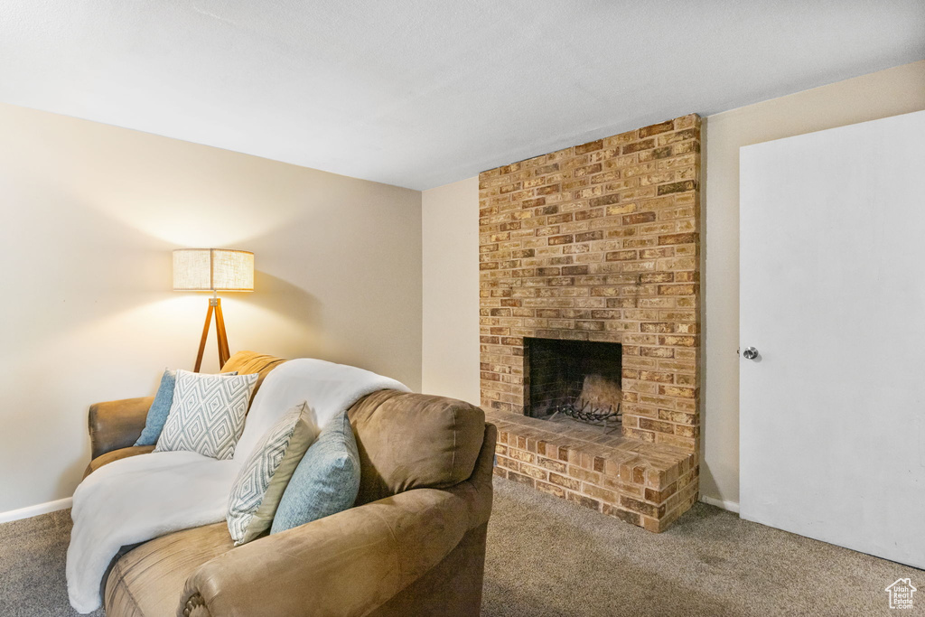 Living area with carpet flooring, a brick fireplace, and baseboards