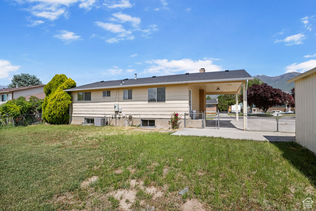 Back of house with central AC, a mountain view, and a gate
