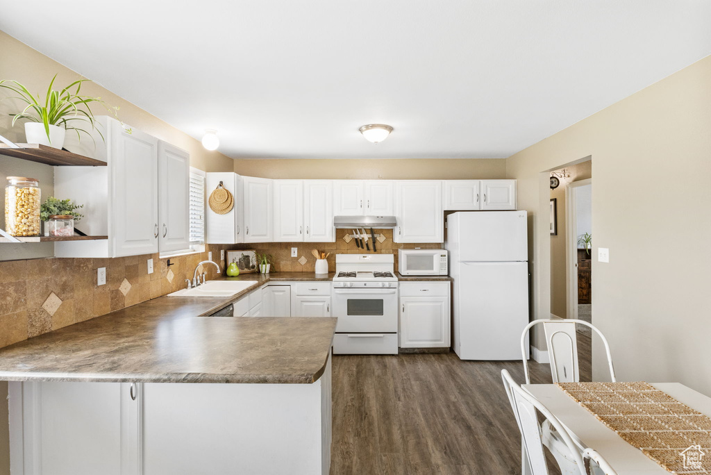 Kitchen featuring white appliances, open shelves, under cabinet range hood, a sink, and dark wood-style flooring