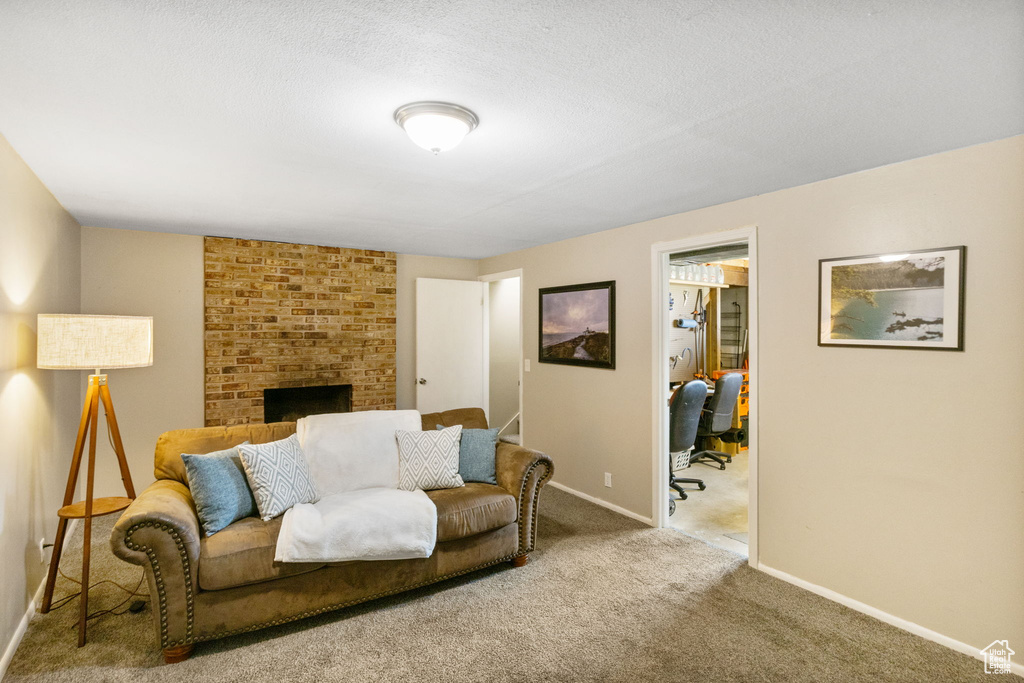 Living area with carpet floors, baseboards, a fireplace, and a desk
