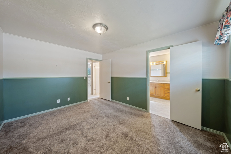 Unfurnished bedroom with carpet, ensuite bath, and baseboards