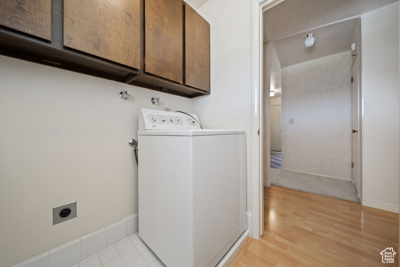 Laundry area featuring washer / dryer, cabinet space, and light wood-style floors
