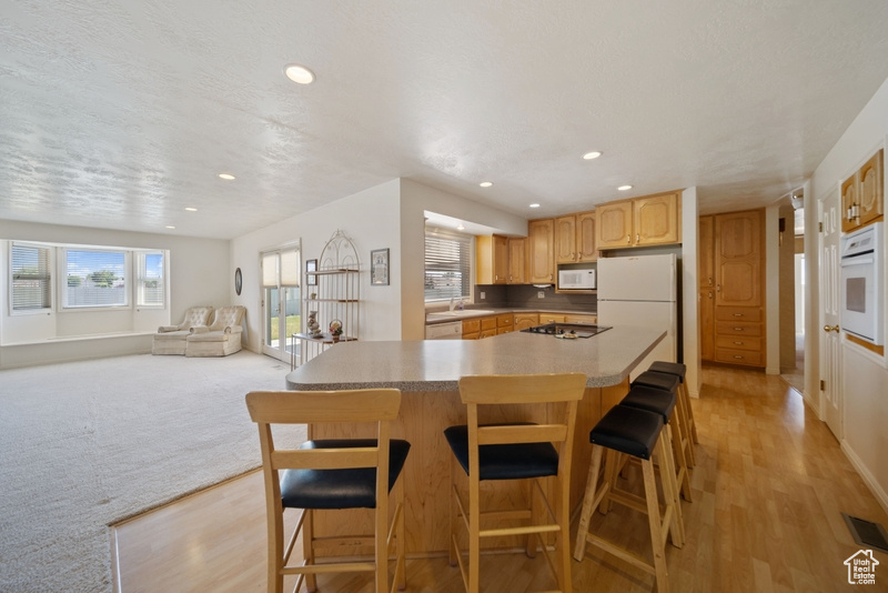 Kitchen featuring white appliances, light wood finished floors, plenty of natural light, and recessed lighting