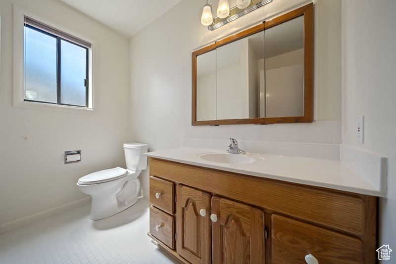 Bathroom with vanity, toilet, baseboards, and tile patterned flooring