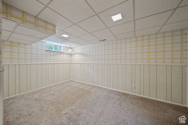 Carpeted spare room featuring a paneled ceiling and wallpapered walls