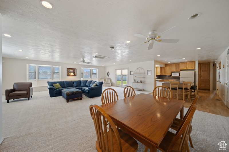 Dining space with a ceiling fan, recessed lighting, and light colored carpet